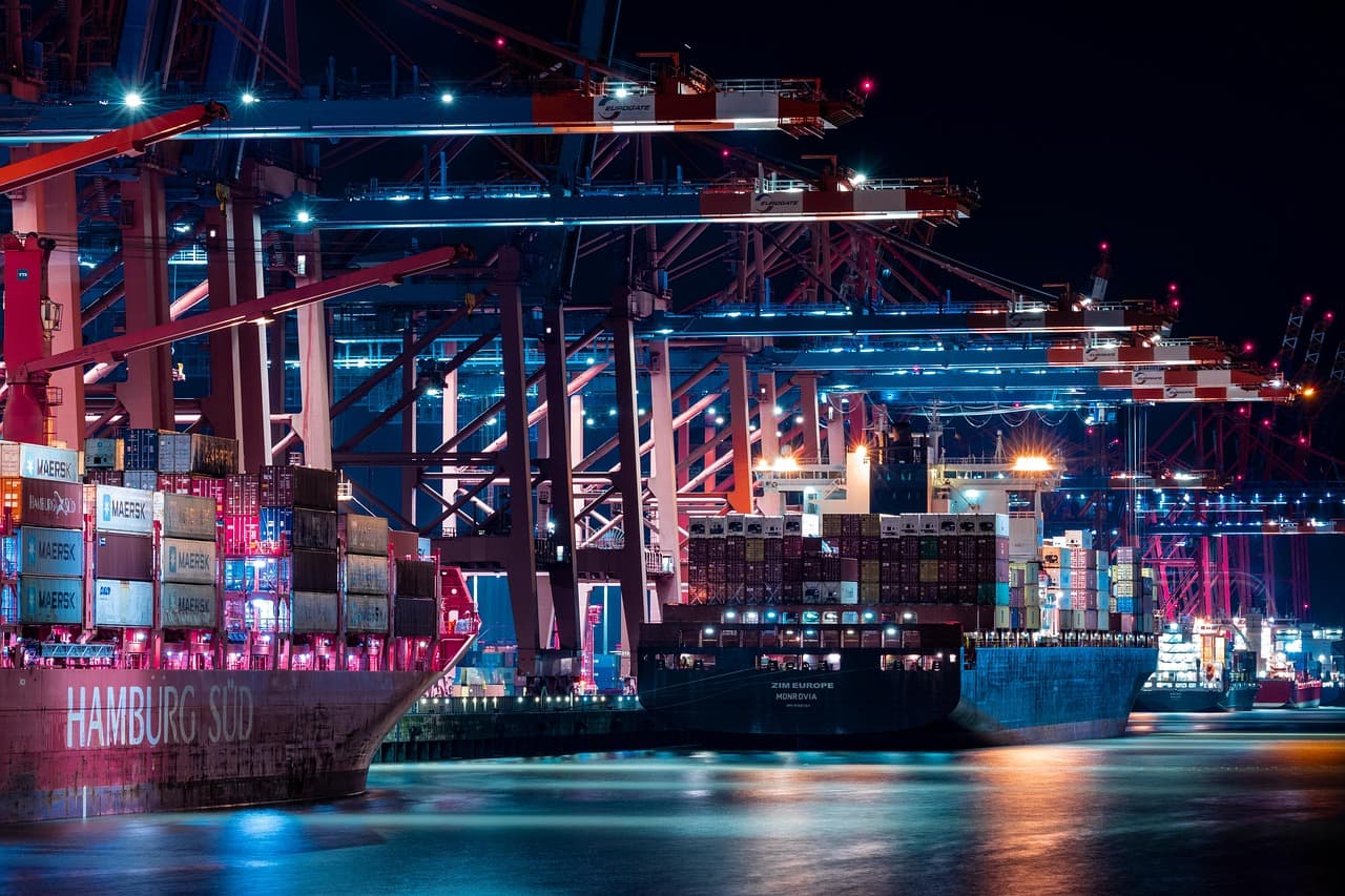 Container shipping port with cranes and cargo vessels at sunset